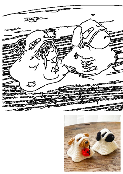 Two small crocheted dogs in Halloween costumes, sitting on a wooden table. One is dressed as a ghost holding a jack-o-lantern bucket.